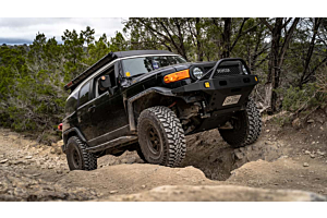 Lifted Toyota Tacoma offroading in the mountains on a sunny day. 