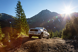 Lifted Toyota Tacoma offroading in the mountains on a sunny day. 