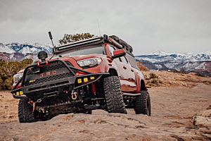 Lifted Toyota Tacoma offroading in the mountains on a cloudy day. 