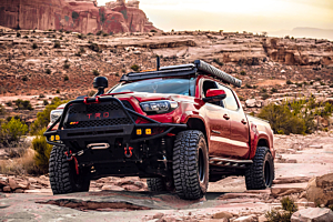 Lifted Toyota Tacoma offroading in the mountains on a sunny day. 