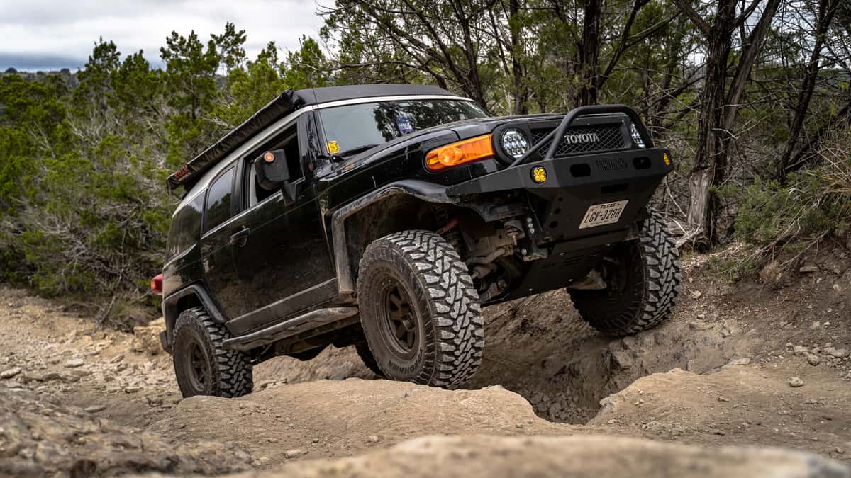 Lifted Toyota Tacoma offroading in the mountains on a sunny day. 