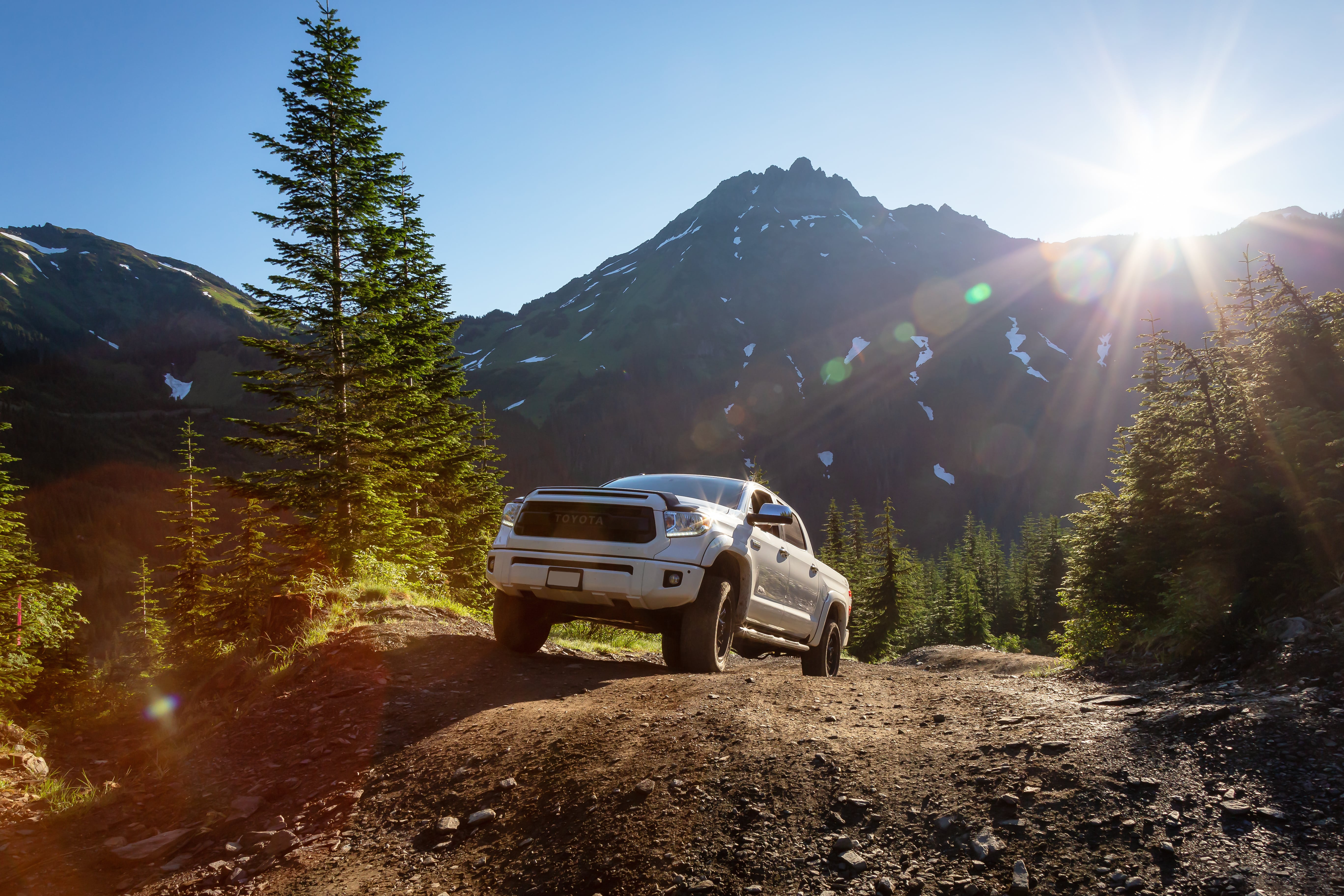 Lifted Toyota Tacoma offroading in the mountains on a sunny day. 