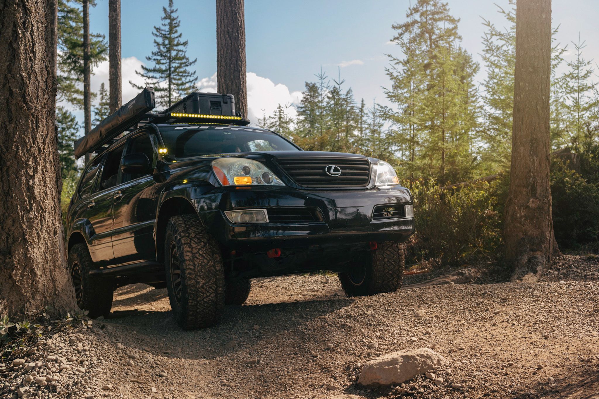 Lifted Toyota Tacoma offroading in the mountains on a sunny day. 