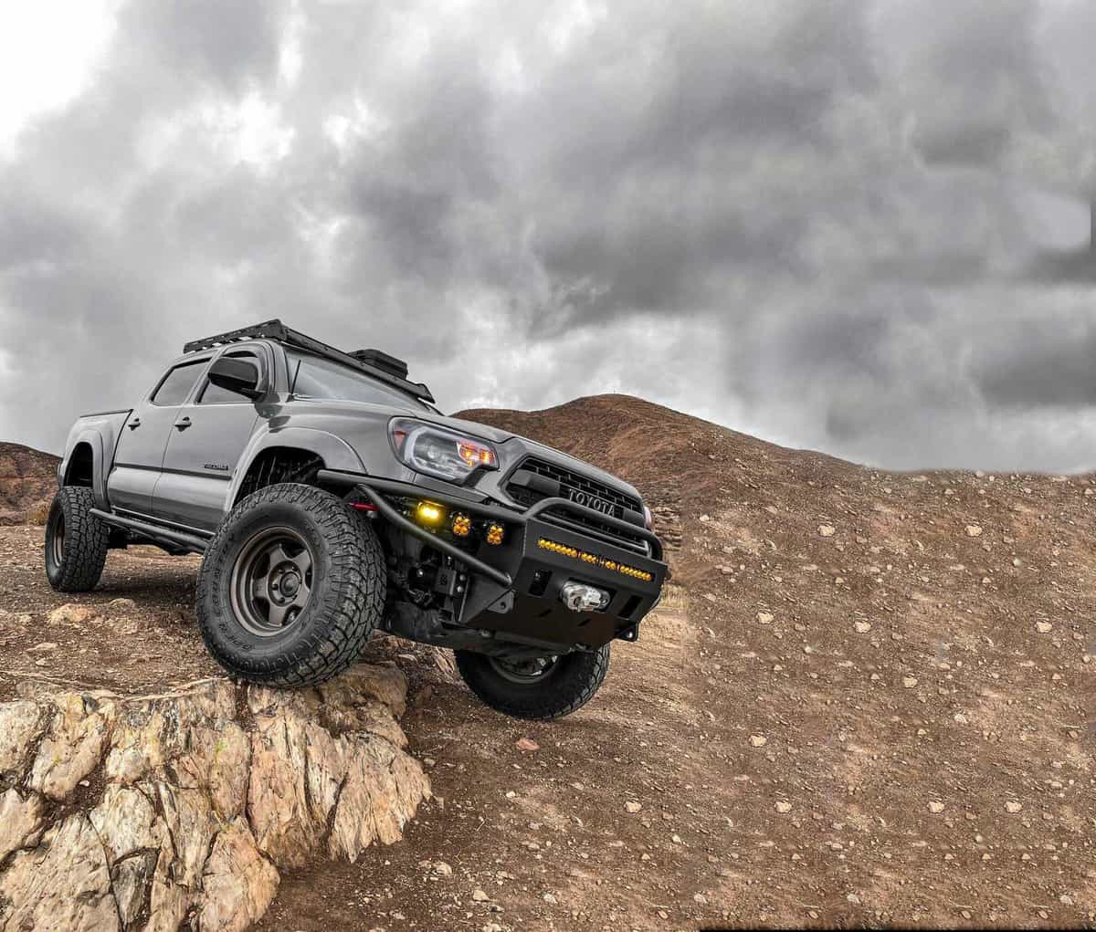 Lifted Toyota Tacoma offroading in the mountains on a cloudy day. 