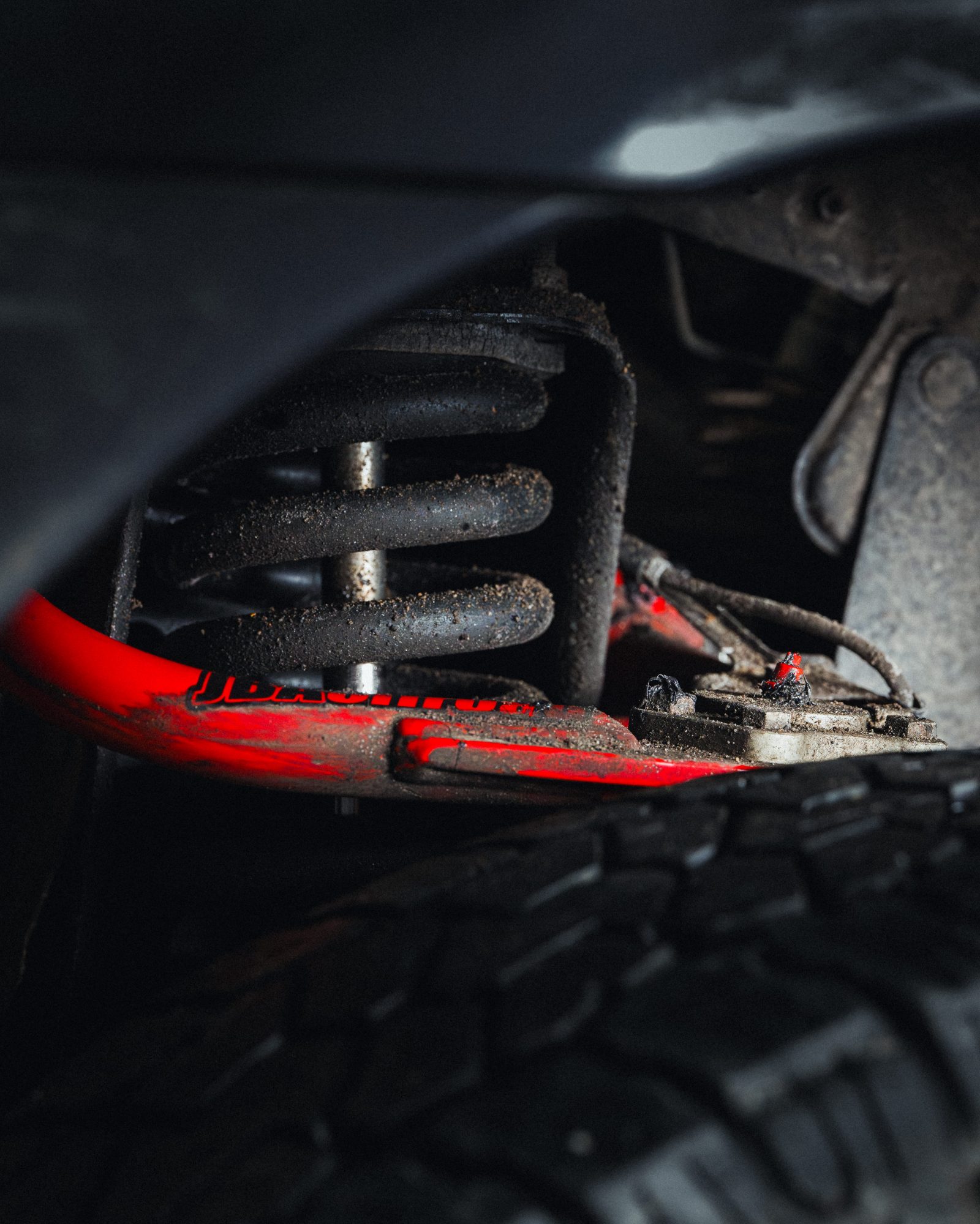 Red JBA High Caster upper control arm installed behind the coilover on a lifted 2nd gen Toyota Tacoma
